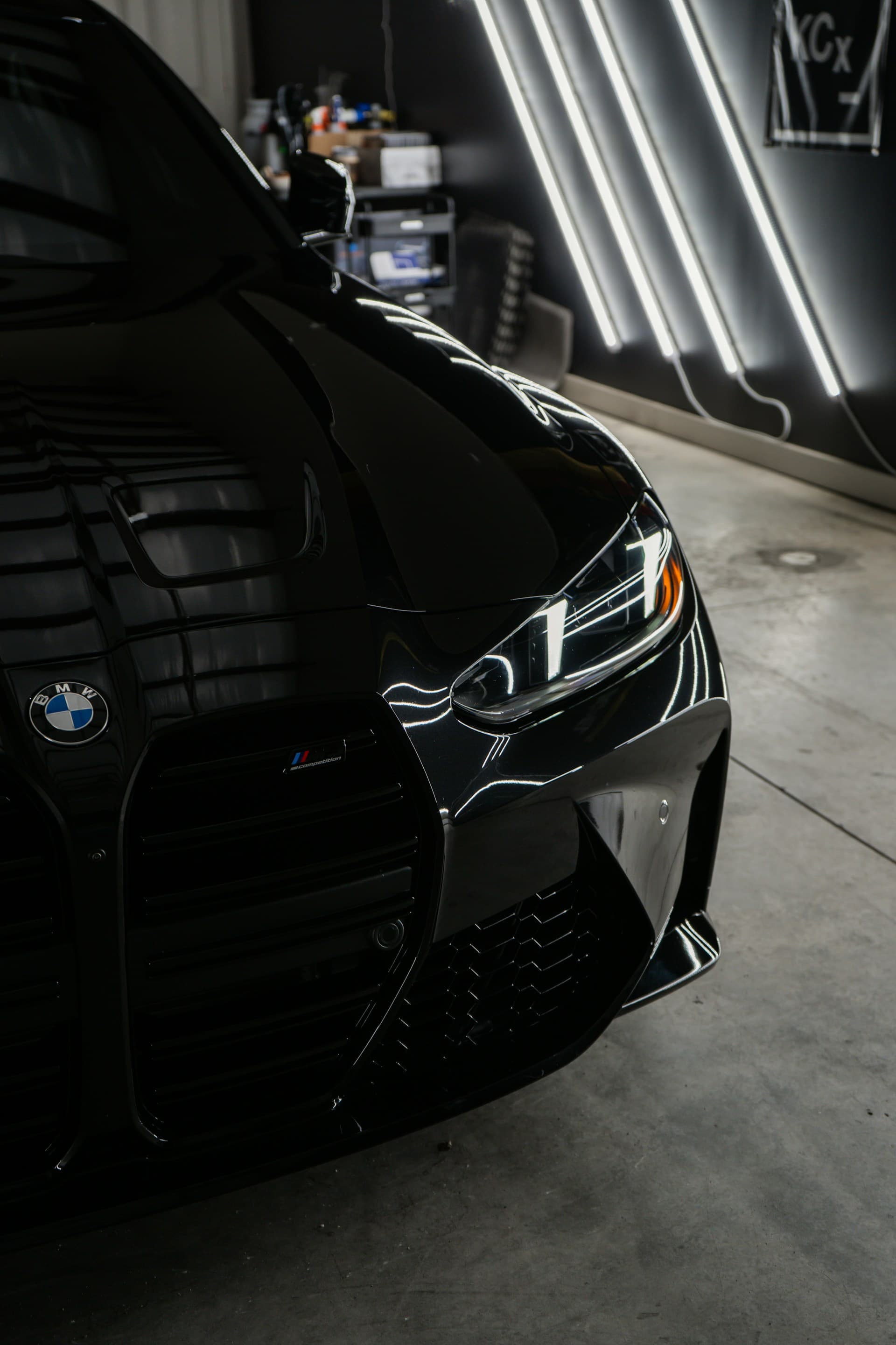 Glossy black BMW M4 reflecting studio lights across its paint