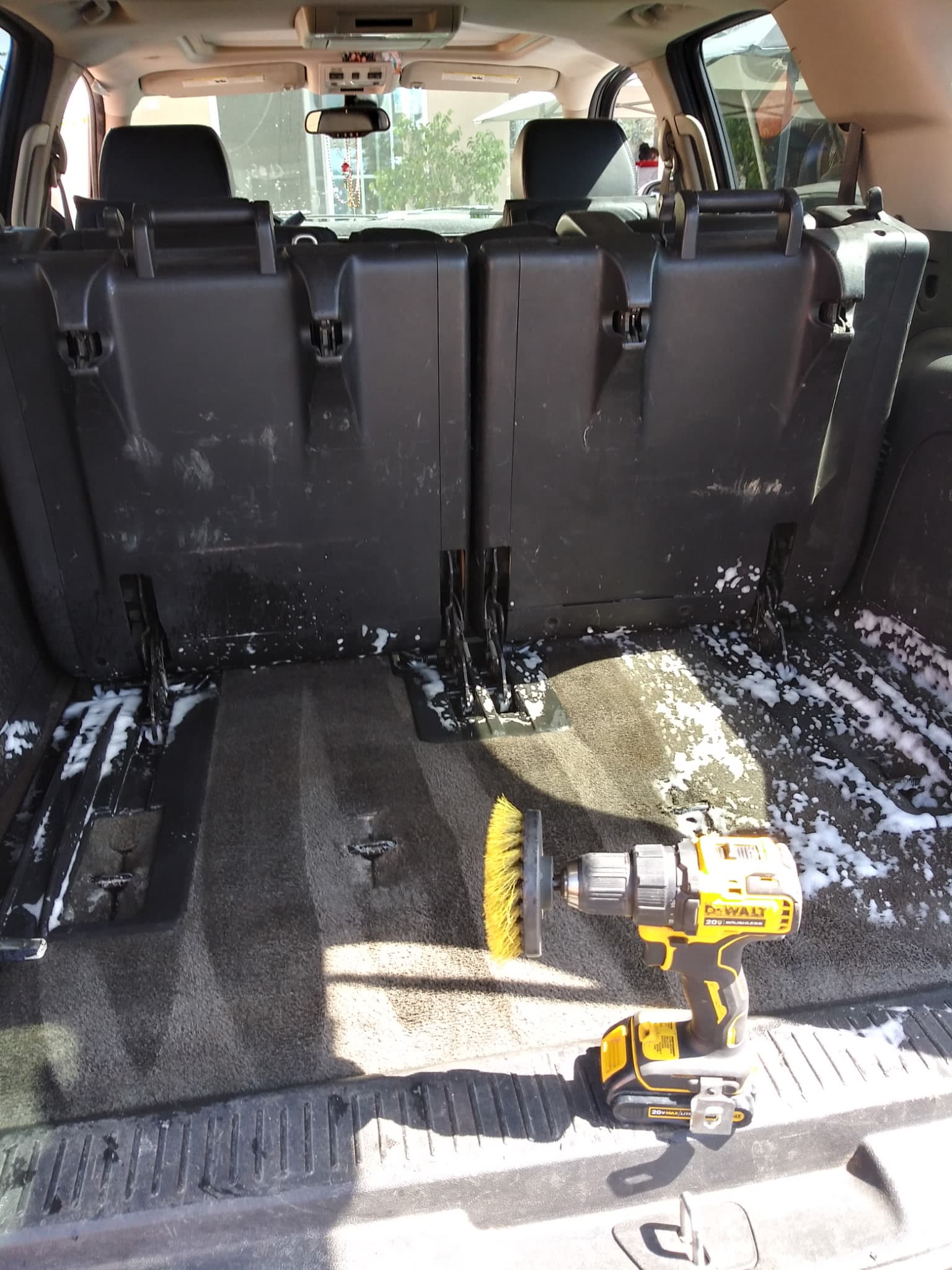 Third-row SUV carpet being shampooed with a powered detailing brush