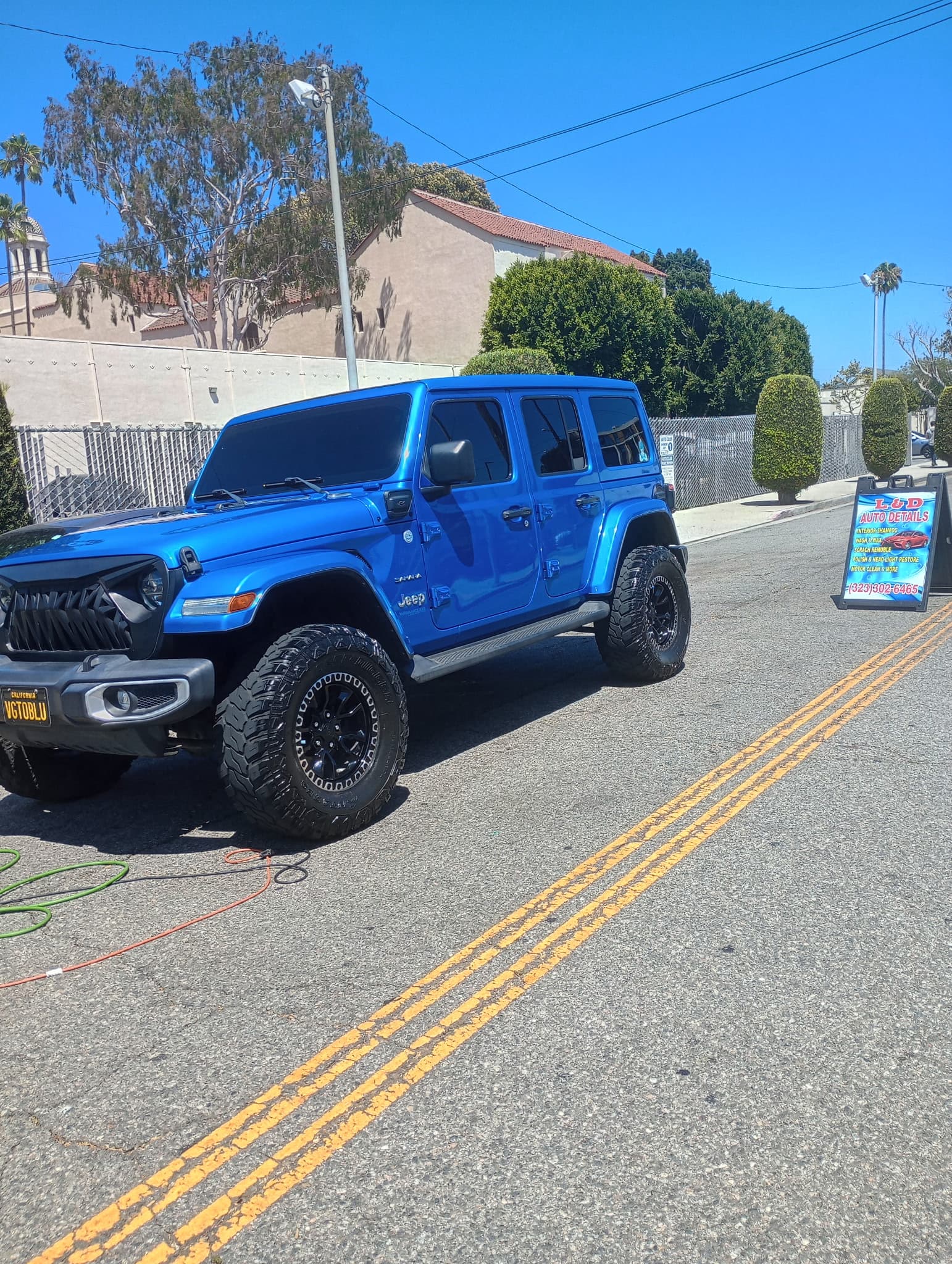 Bright blue lifted Jeep Wrangler detailed curbside in Los Angeles